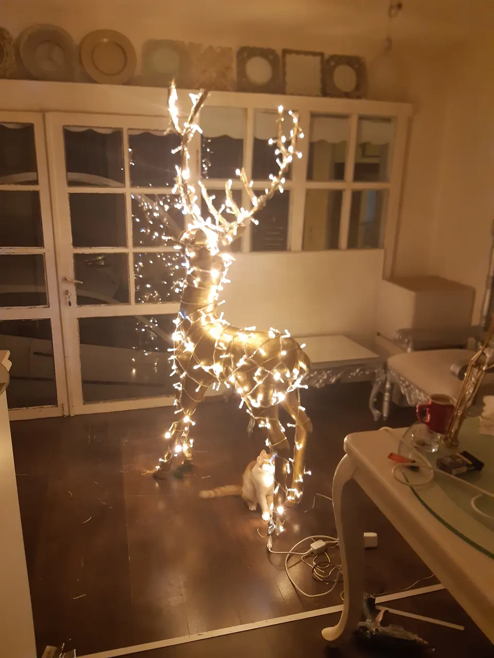 Pencere önünde duran ışıklı geyik figürü